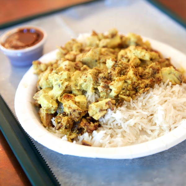 Hampton Chutney Co. chicken curry with rice and a side of chutney in a paper bowl.