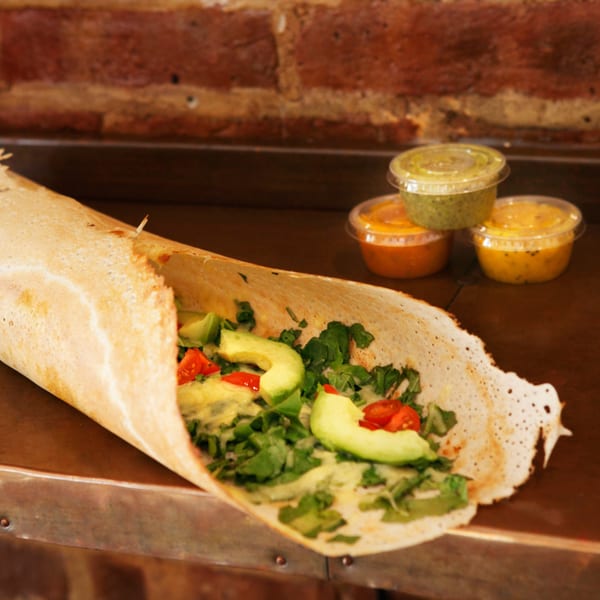 Hampton Chutney Co. dosa filled with avocado, tomatoes, and greens, with three chutneys.