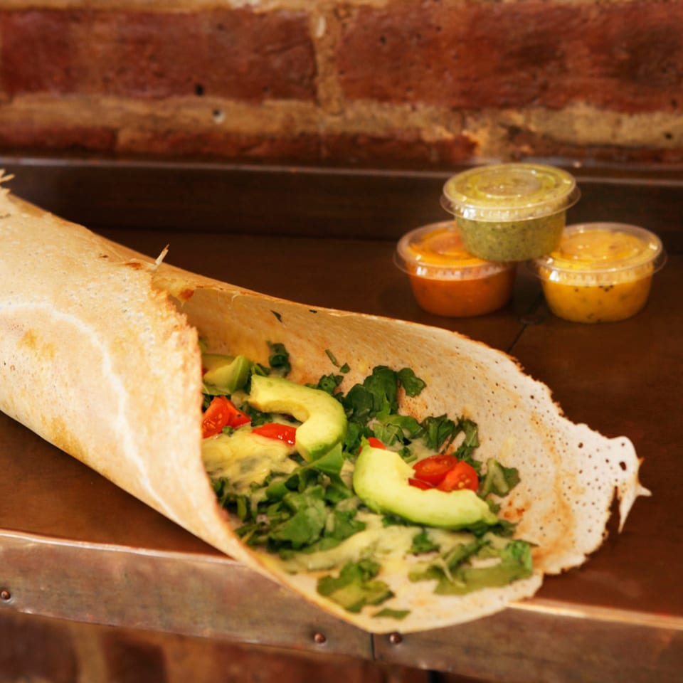 Hampton Chutney Co. dosa filled with avocado, tomatoes, and greens, with three chutneys.