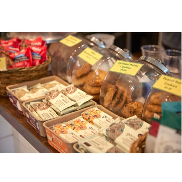 A counter display with glass jars of cookies and boxes of packaged snack bars.