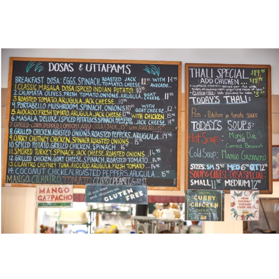 Chalkboard menus at Hampton Chutney Co. display Indian dosas, thali specials, and soups.