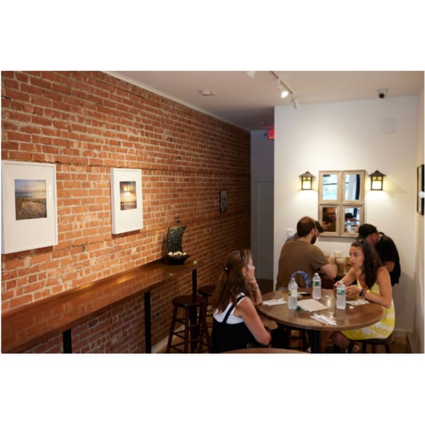 Customers seated at tables and a bar in a Hampton Chutney Co. dining area with brick walls.