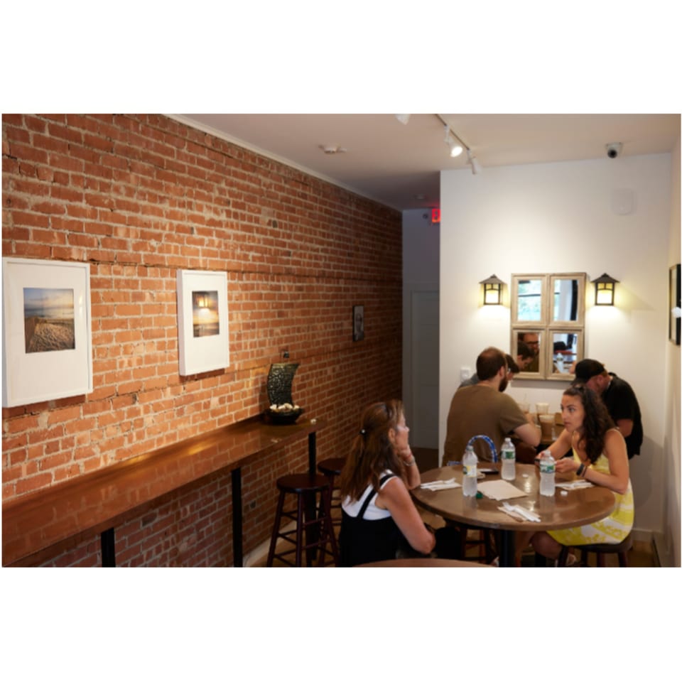 Customers seated at tables and a bar in a Hampton Chutney Co. dining area with brick walls.