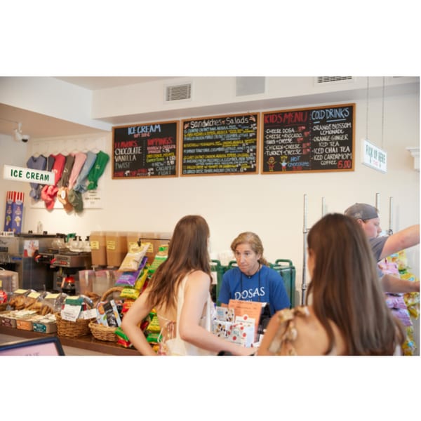 Customers ordering at the counter of Hampton Chutney Co., with menus displayed above.