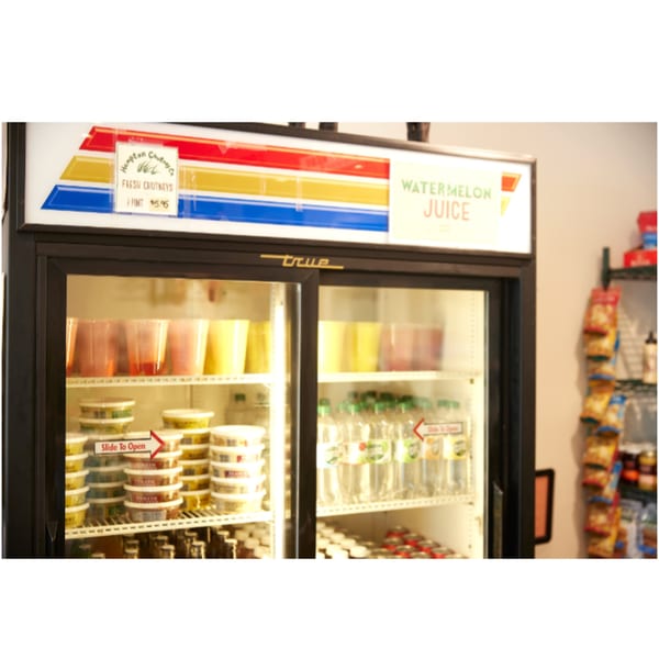 A Hampton Chutney Co. refrigerated display case filled with fresh chutneys, juices, and bottled water.