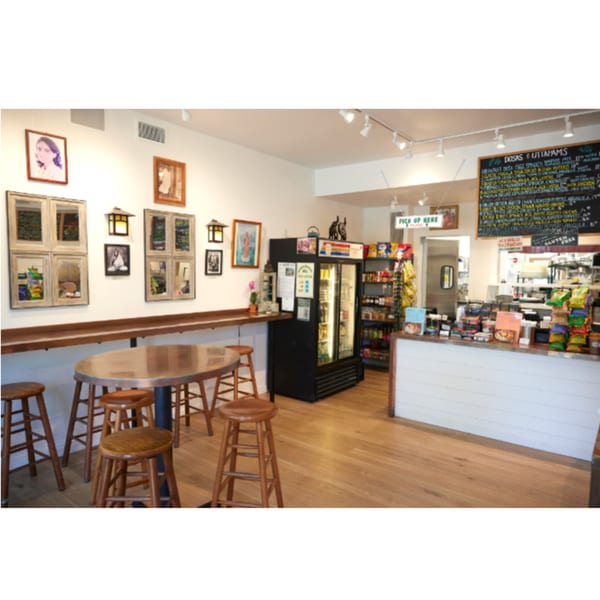 Interior of Hampton Chutney Co. with a long bar, high tables, and a menu board.